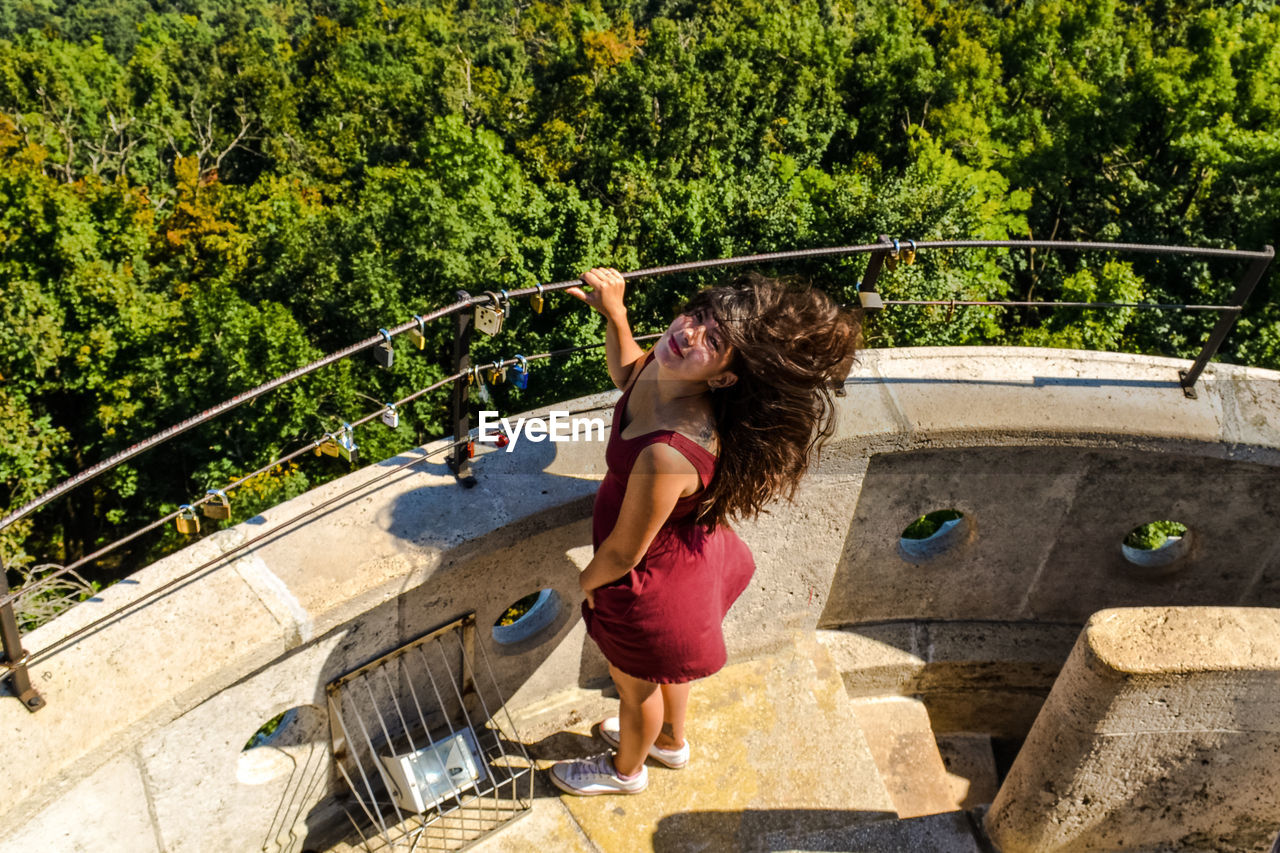 Girl with black hair fluttering stands on elizabeth lookout on janos hill in budapest, hungary