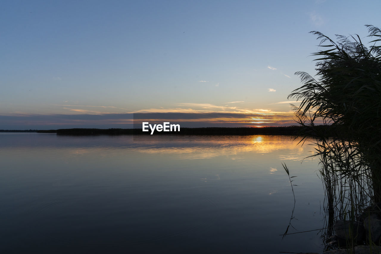 SCENIC VIEW OF LAKE AT SUNSET