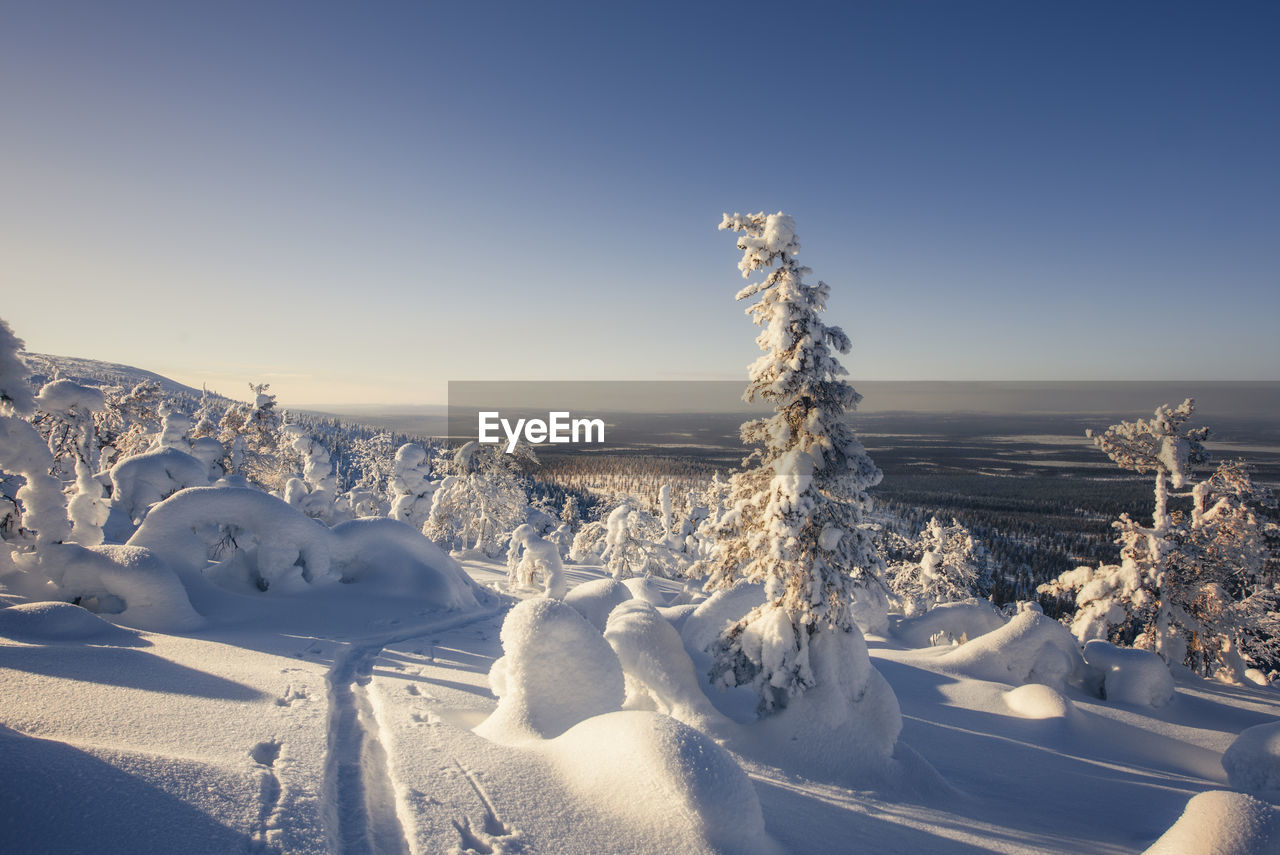 Snow covered landscape against clear sky