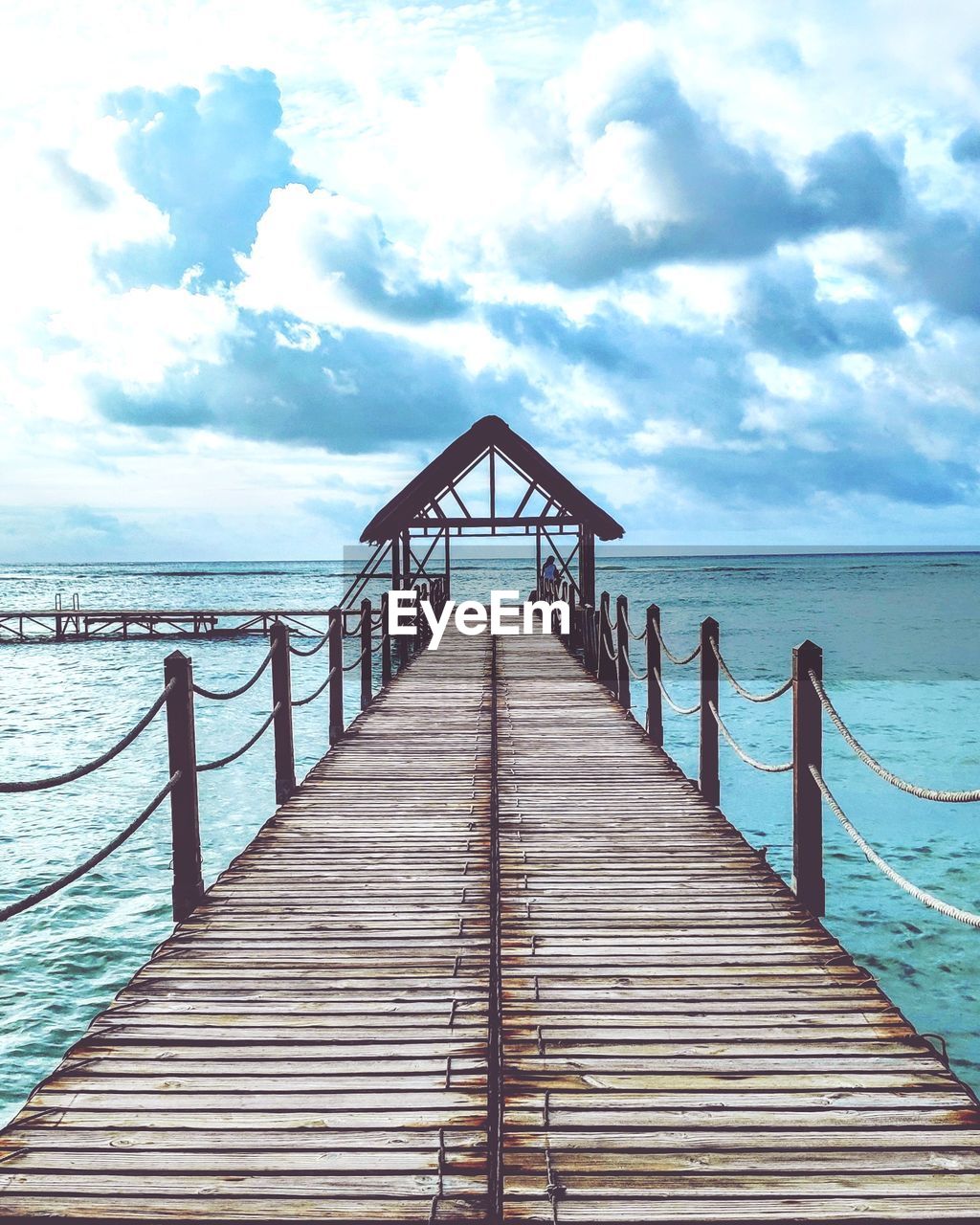 WOODEN PIER ON BEACH AGAINST SKY