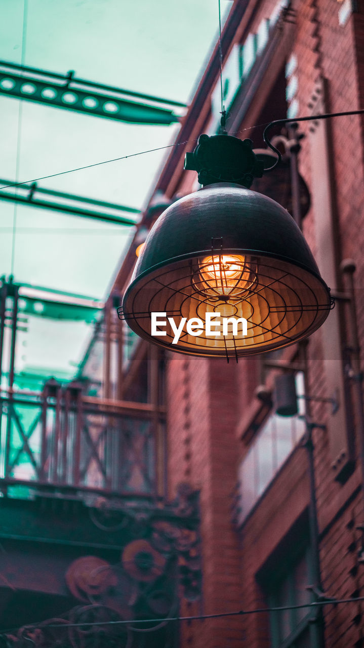 Low angle view of illuminated pendant lights hanging on ceiling of building