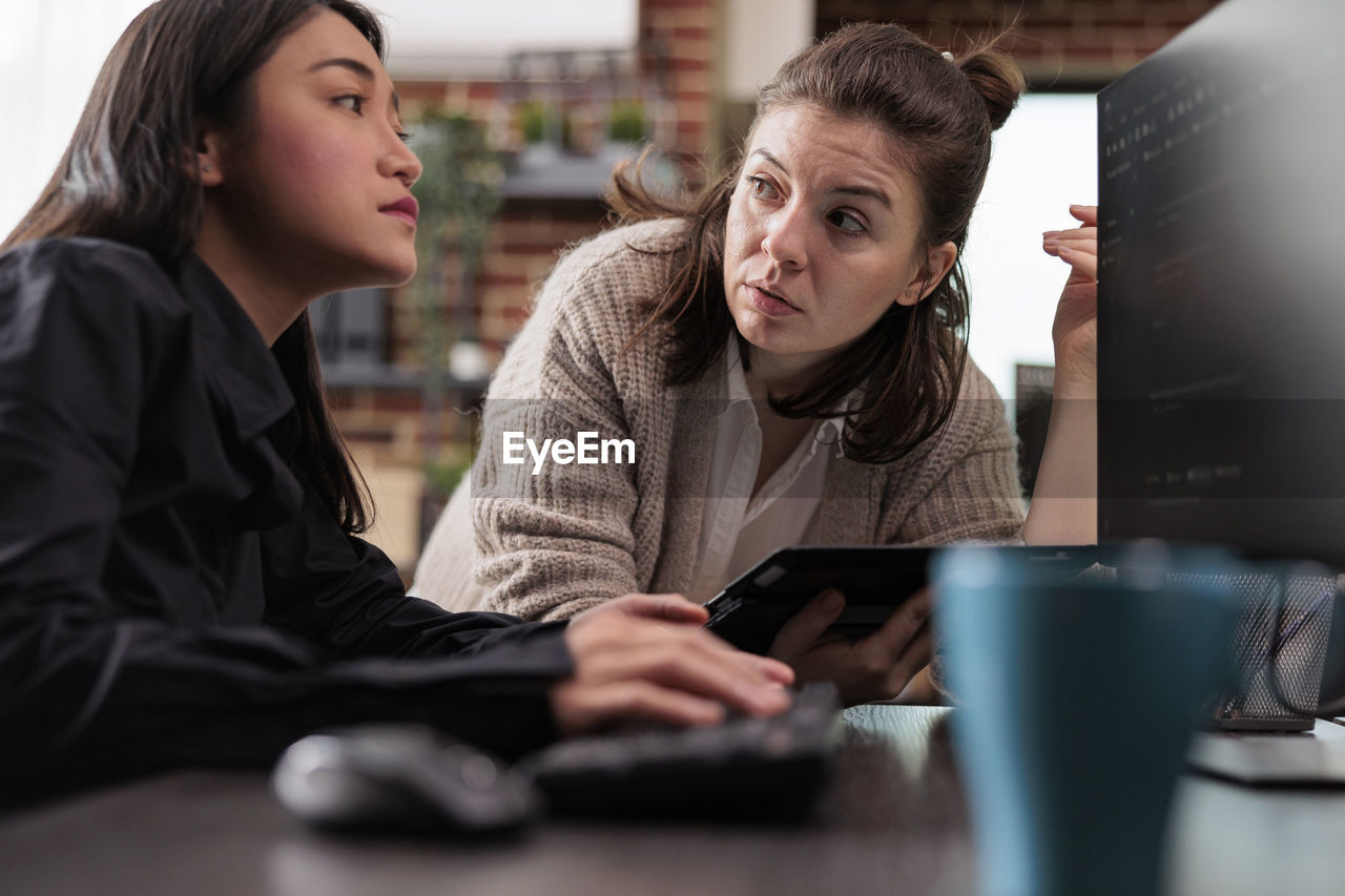 portrait of young woman using laptop at table in office