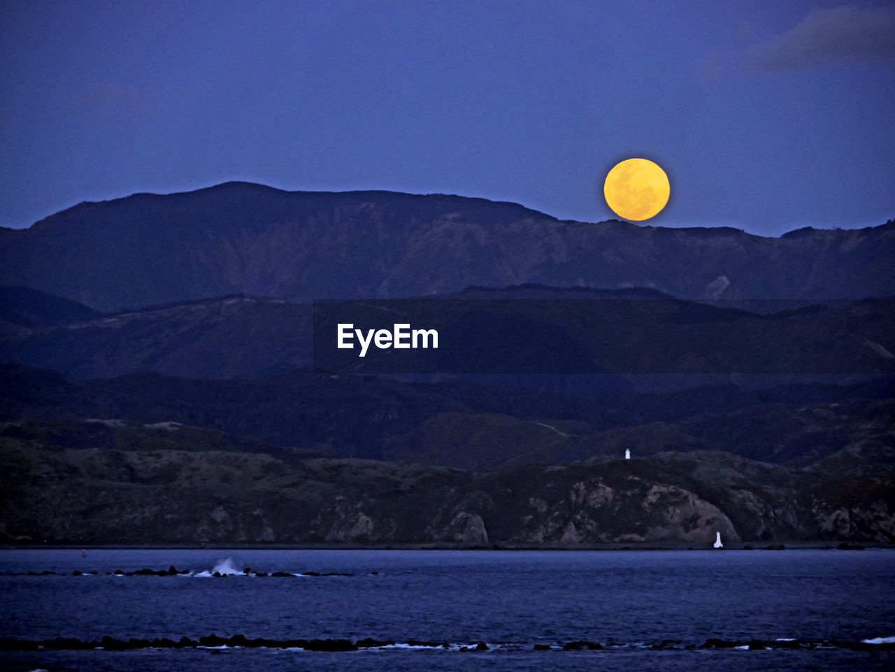 Scenic view of moon over mountains against sky at night