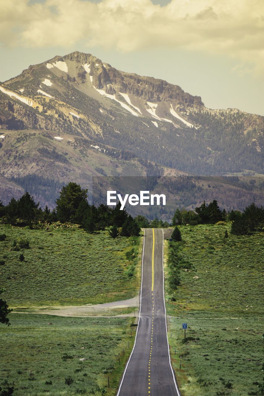 Road leading towards mountains against sky