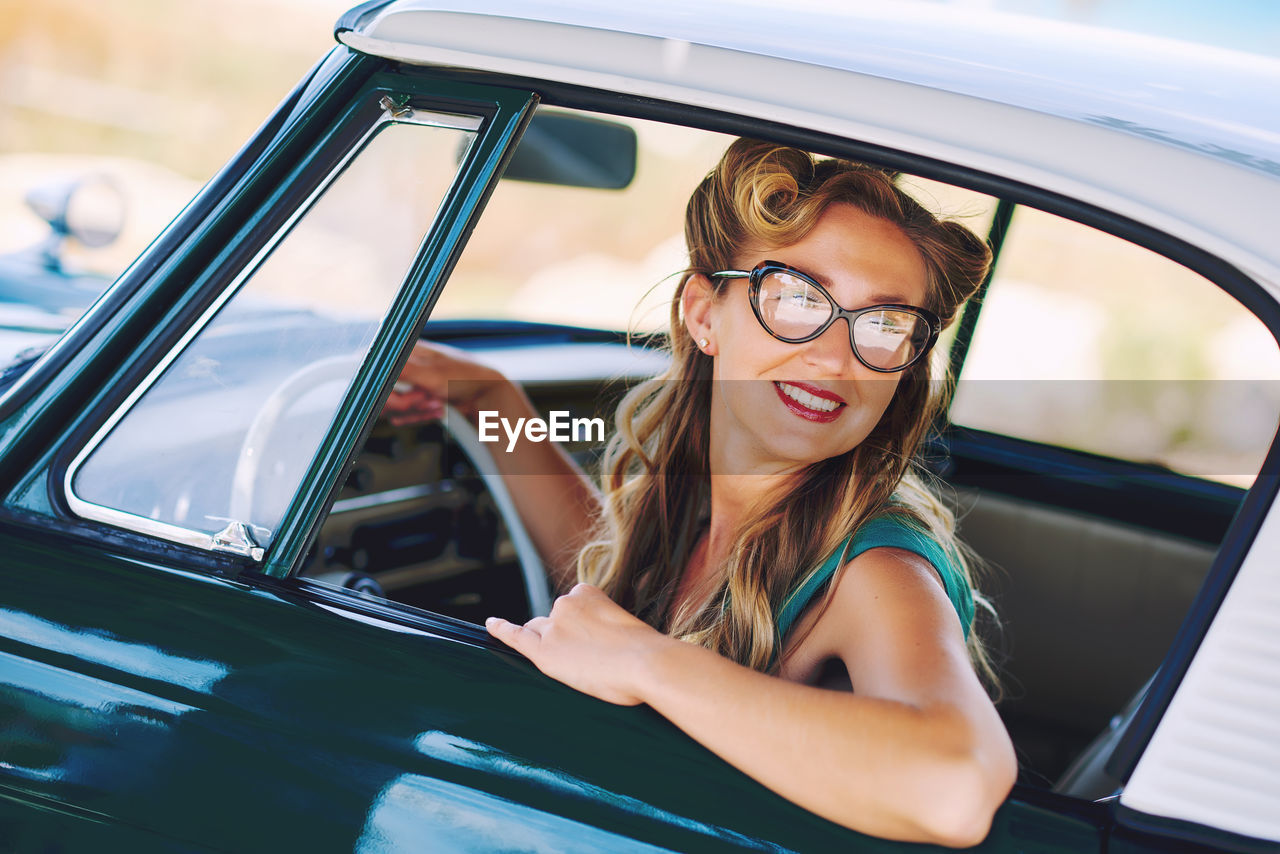 Portrait of smiling young woman sitting in car