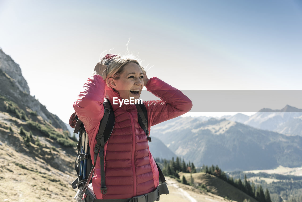Austria, tyrol, happy woman on a hiking trip in the mountains enjoying the view