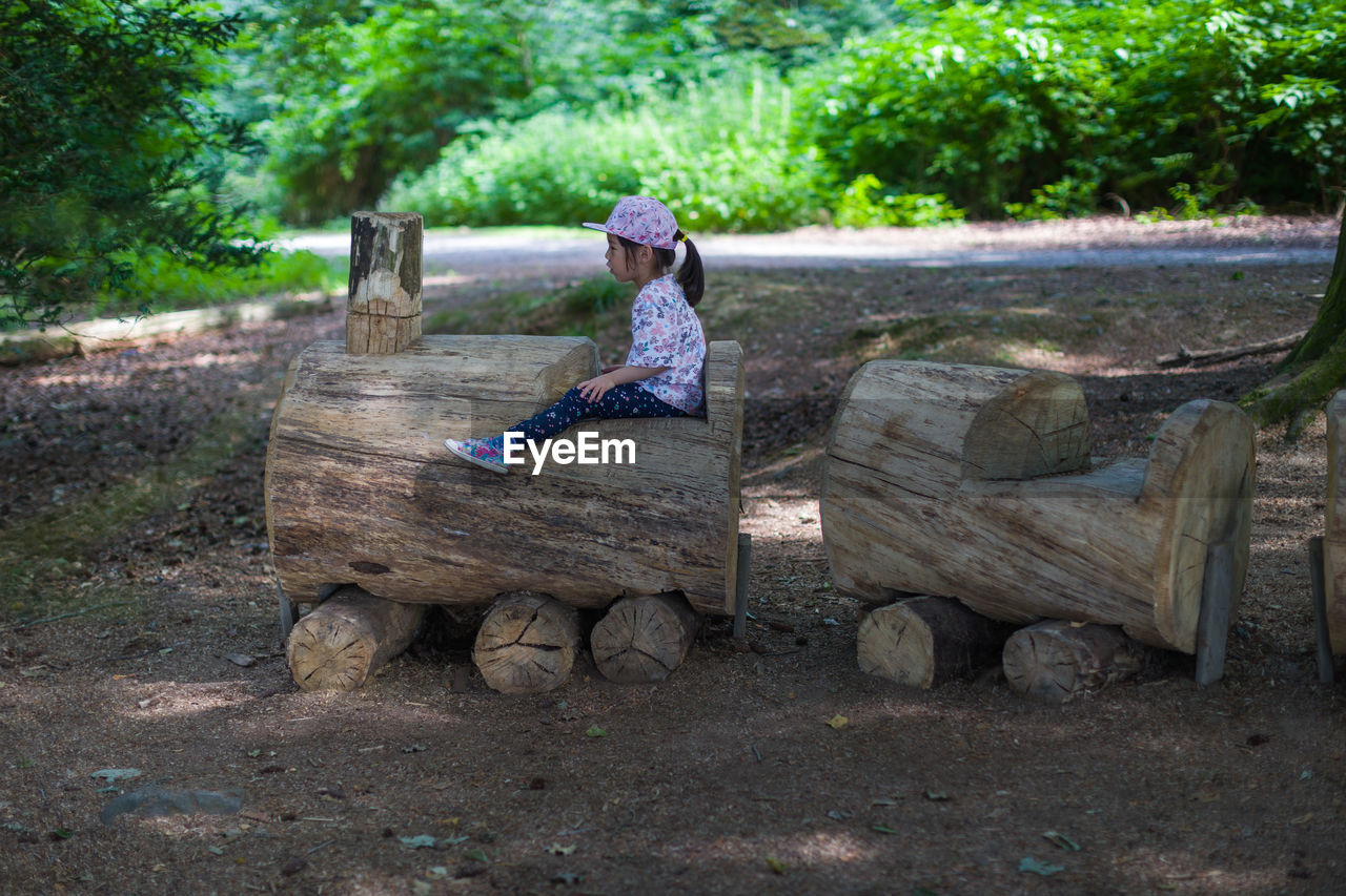 REAR VIEW OF WOMAN SITTING ON BENCH IN PARK