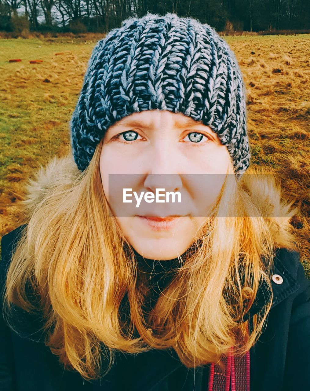 Portrait of woman wearing knit hat while standing on field