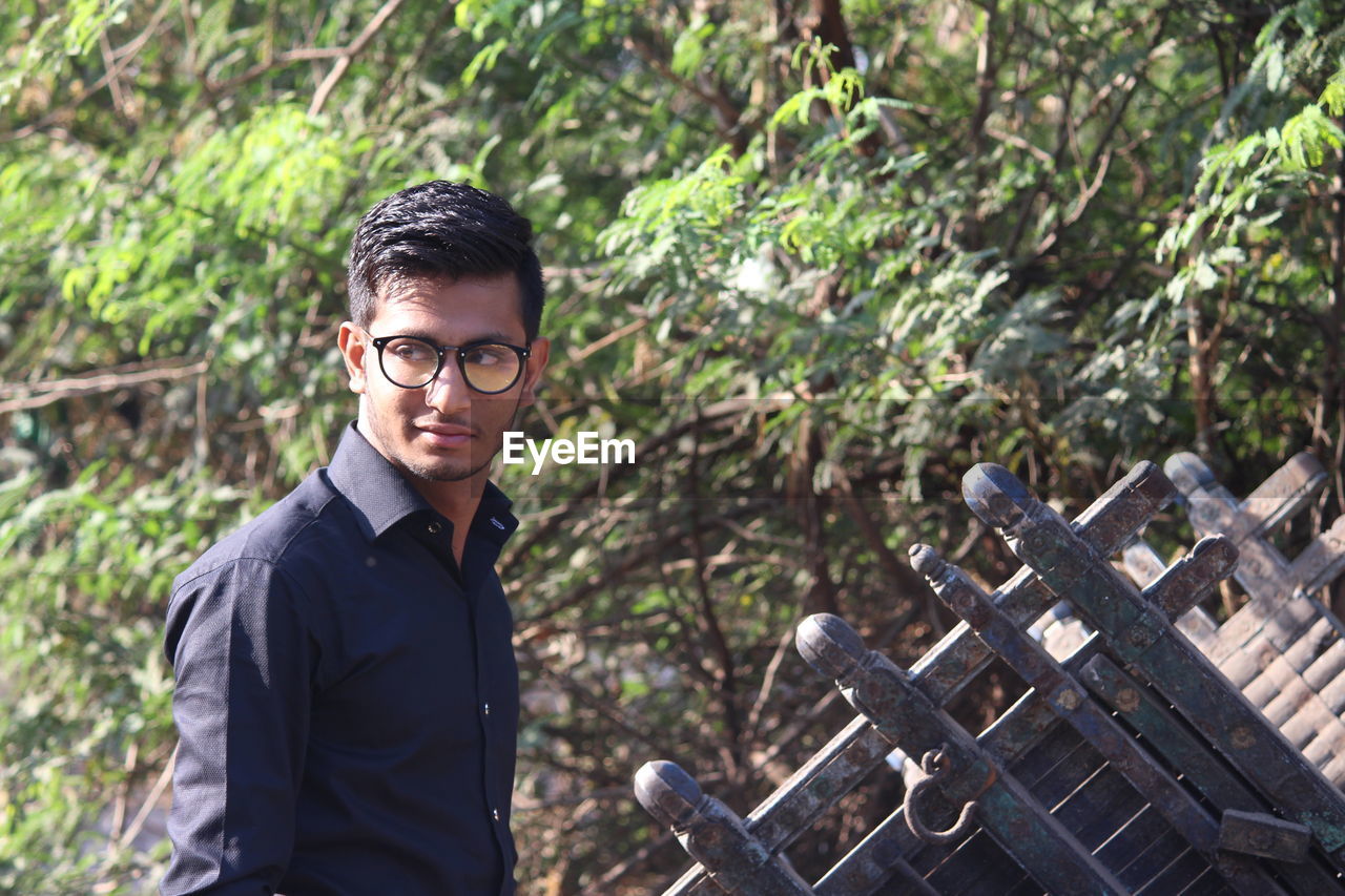 Close-up of young man standing against plants