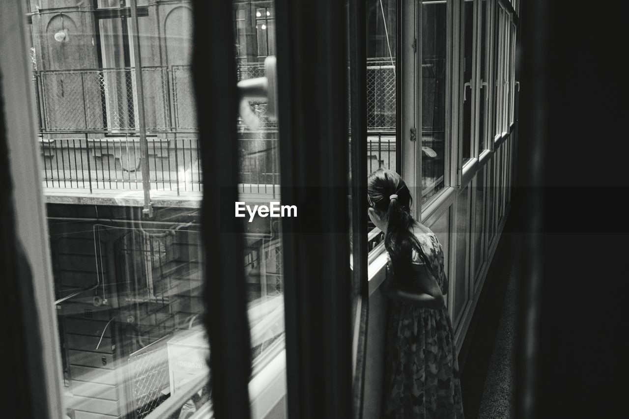 Girl looking through window in old building