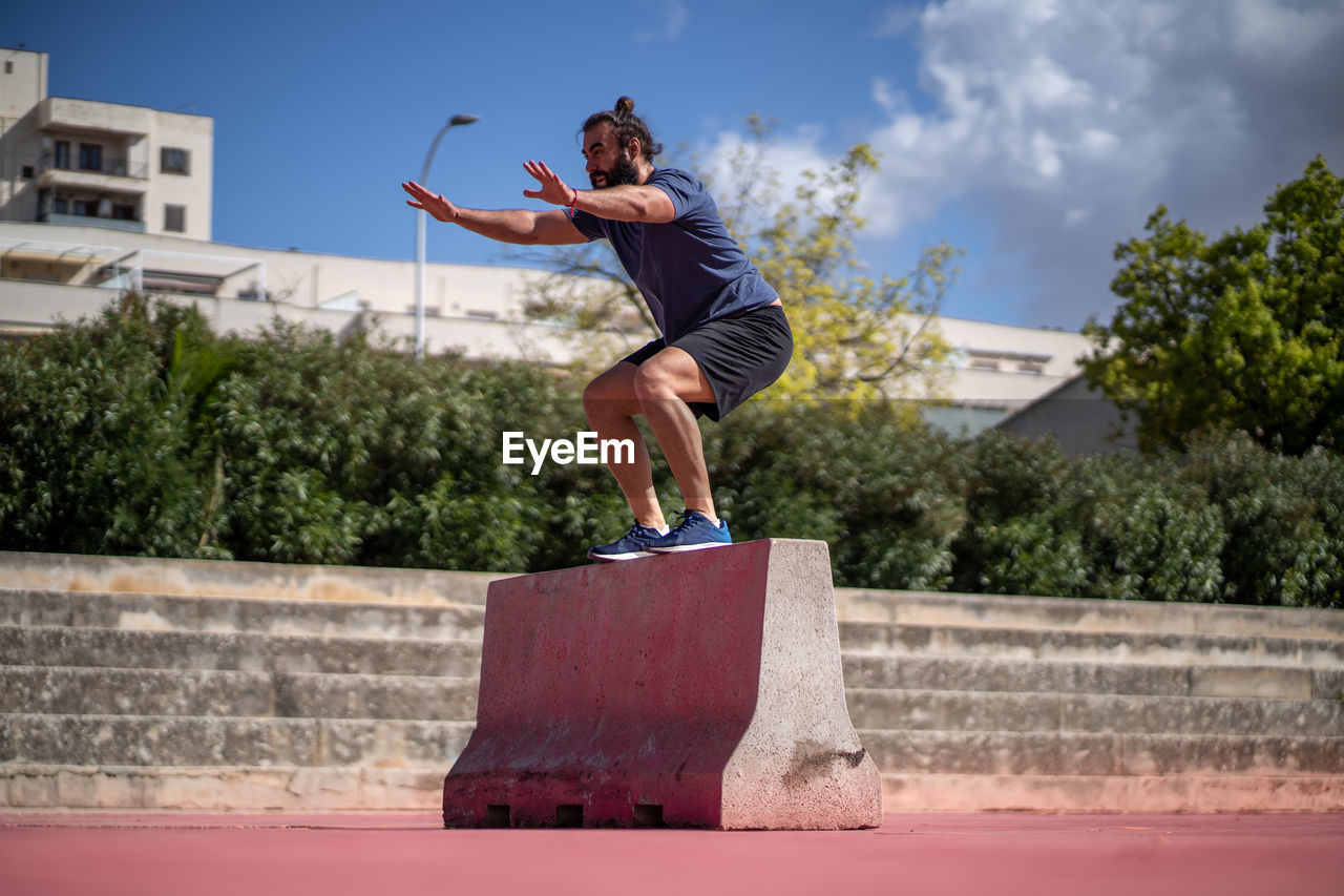 Man trains with squat jumps on a platform in the middle of a court