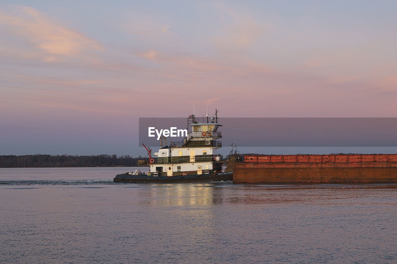 A push boat moving barges up the tennessee river on a december afternoon just before sunset.