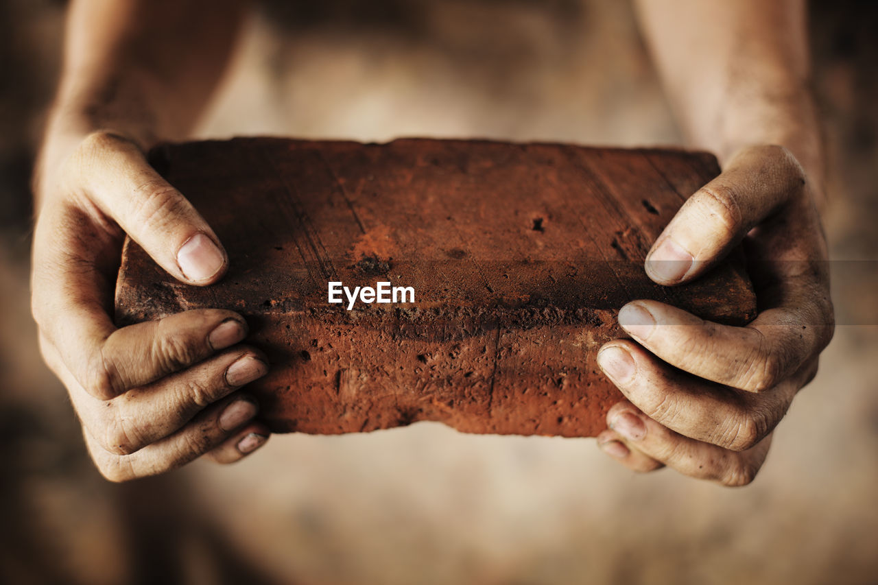 Close-up of hands holding brick