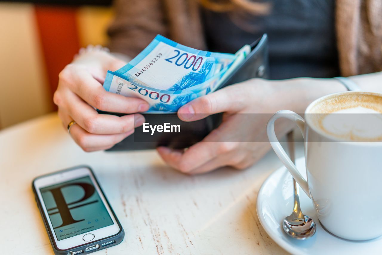 Cropped hands of woman paying bill at cafe