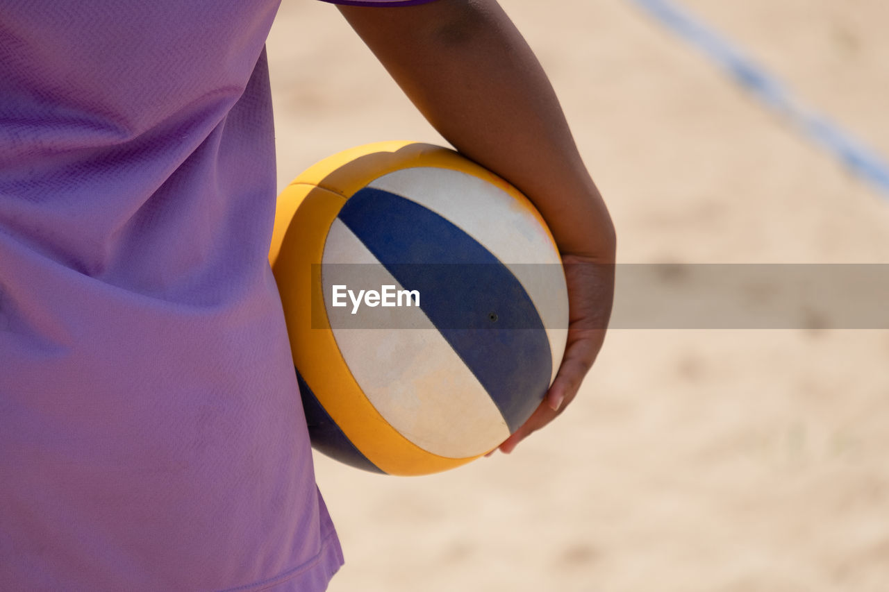 Close-up of person holding ball on sand