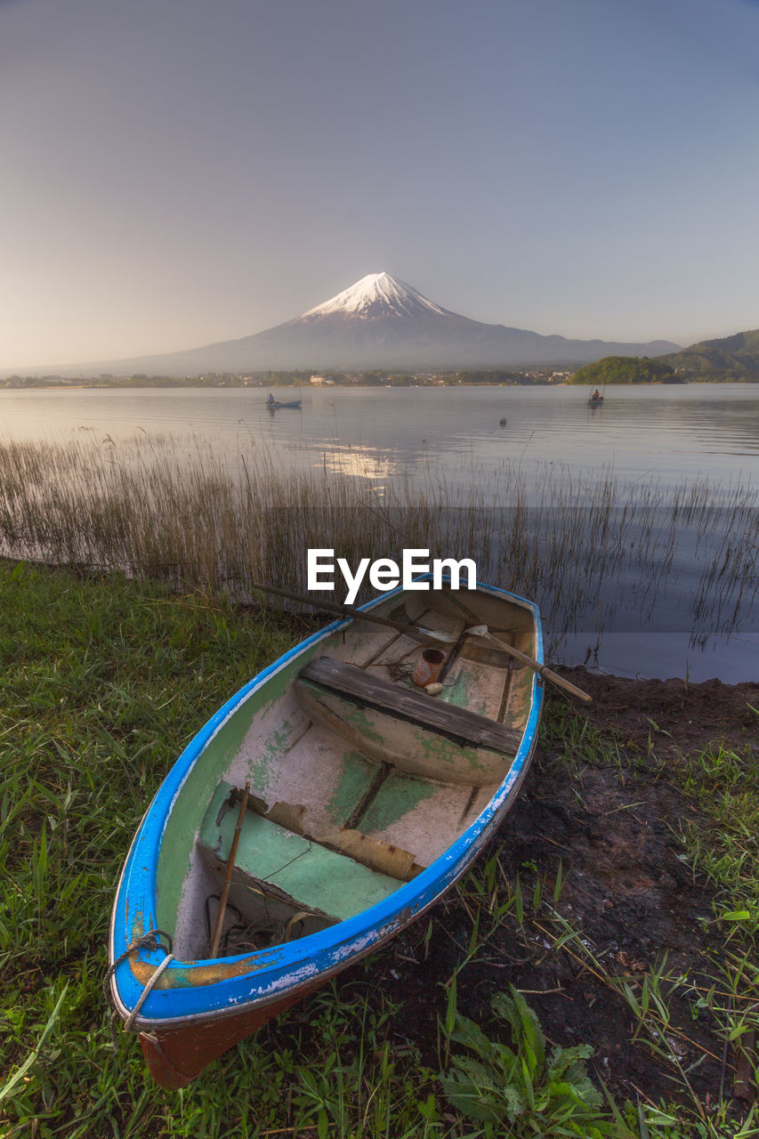 Boat moored by lake against mt fuji