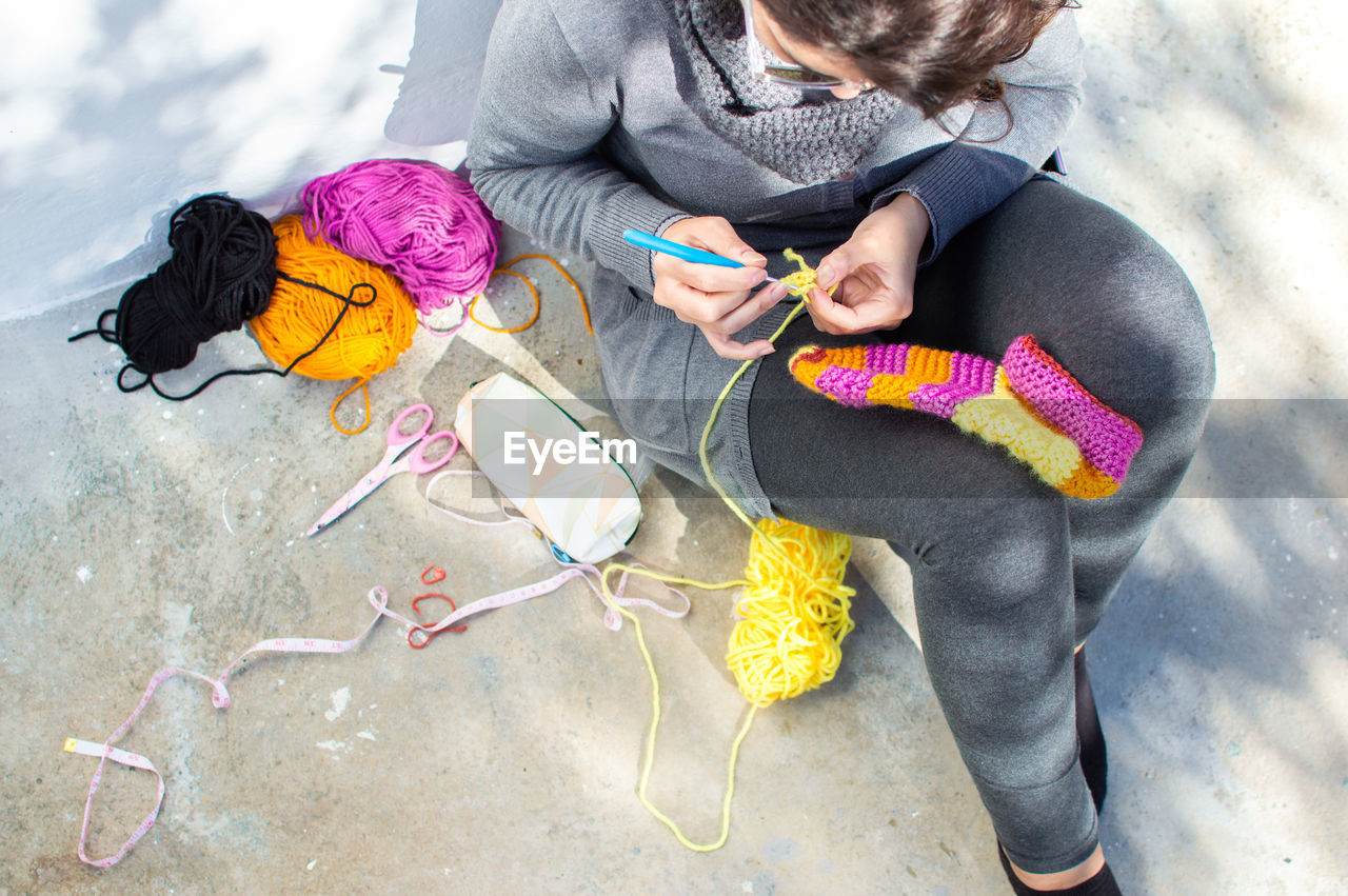 HIGH ANGLE VIEW OF WOMEN SITTING ON MULTI COLORED HOLDING UMBRELLA