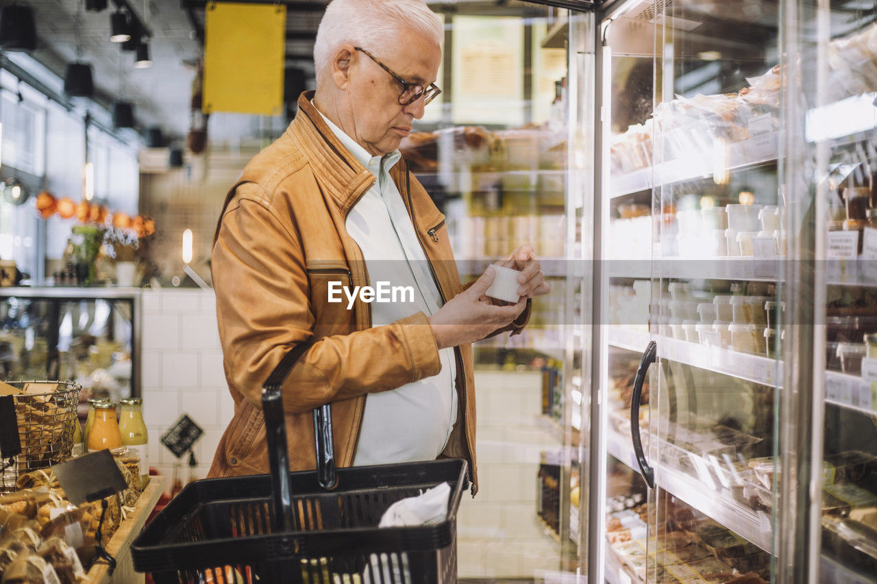 Senior man analyzing container at grocery store