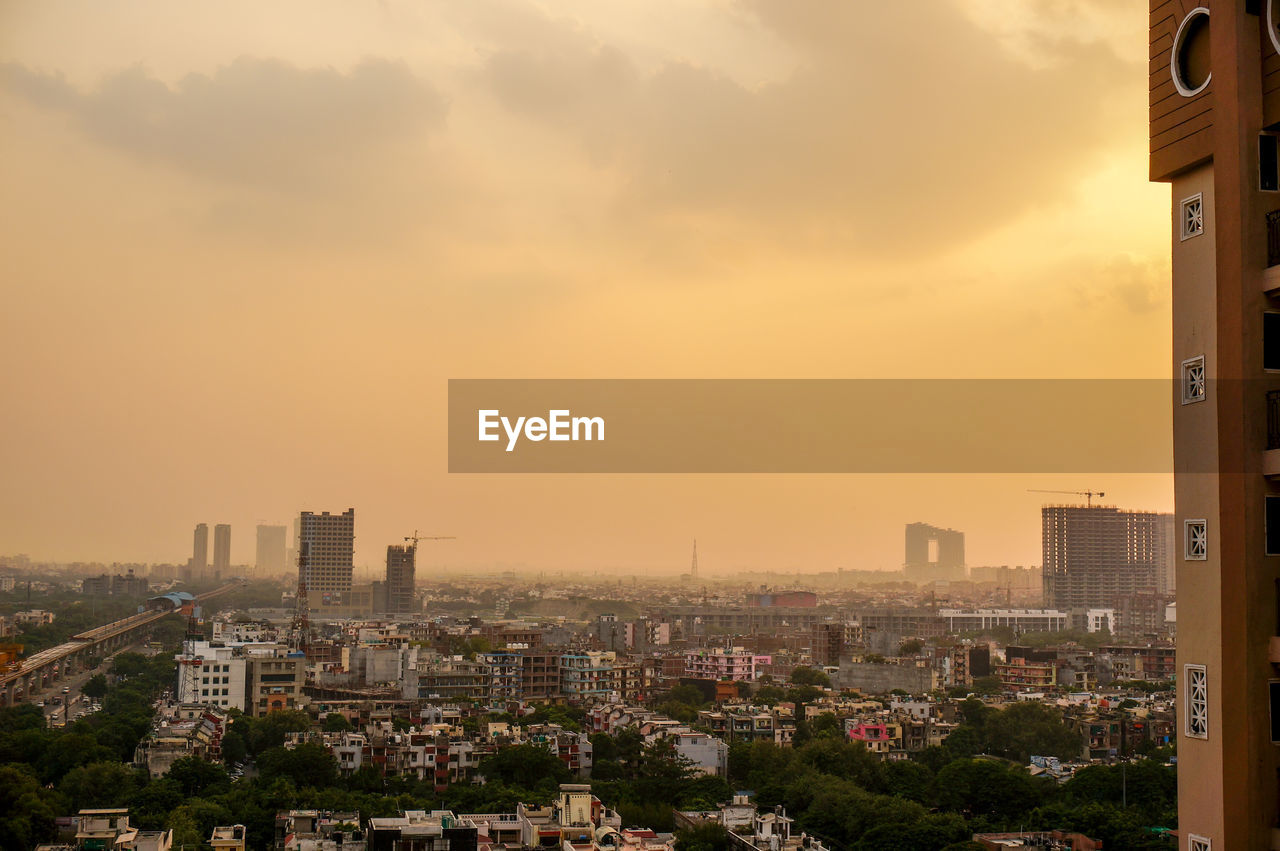 View of cityscape against cloudy sky during sunset