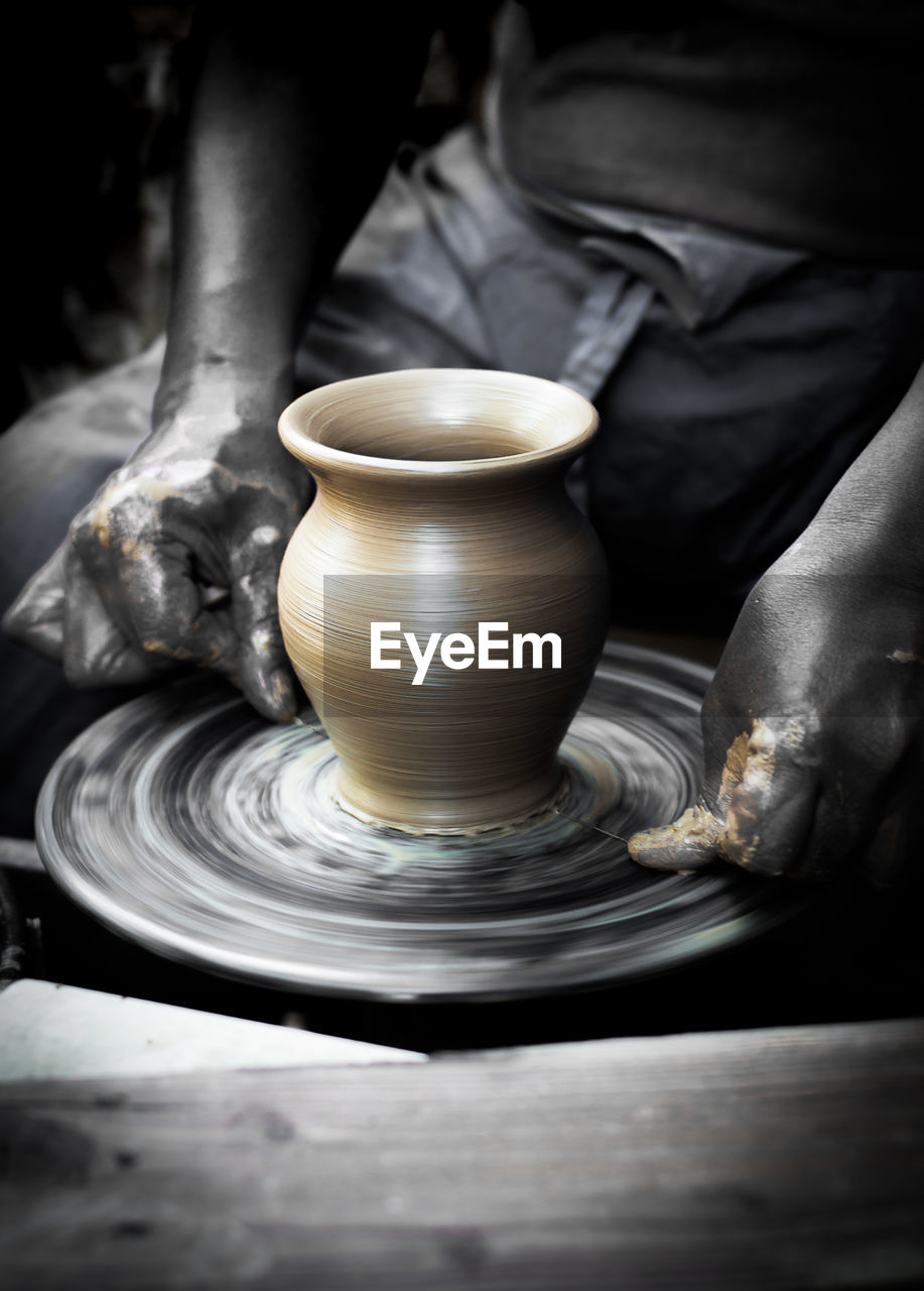 Midsection of man making pot in workshop