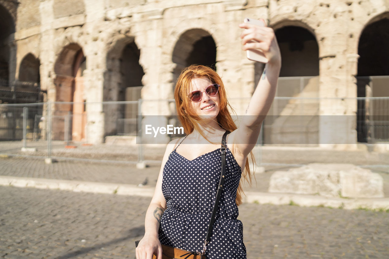 Cheerful tourist taking selfie on street