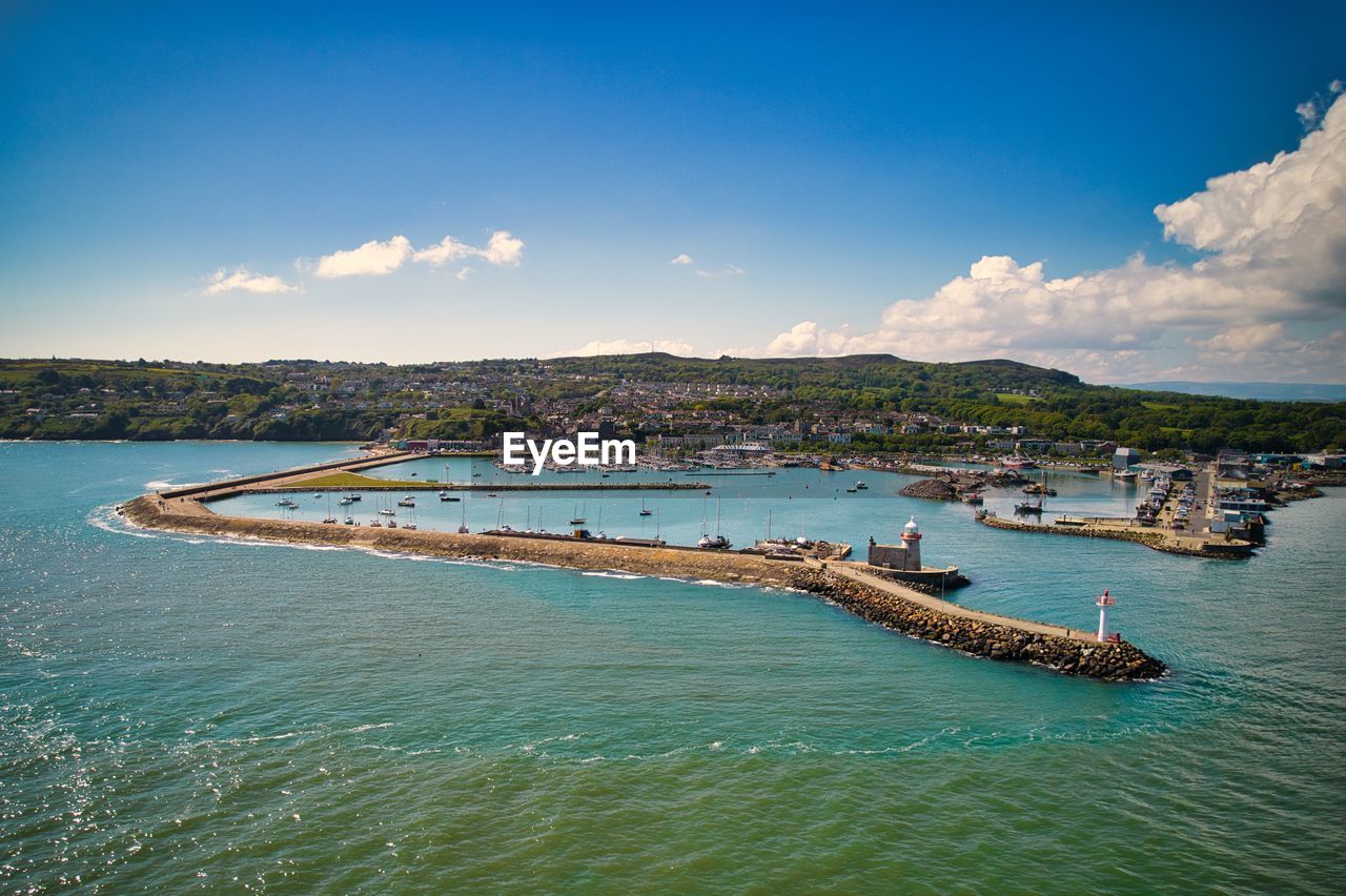 Aerial view of howth town with lighthouse, marina, pier, boats and hills in the background. 
