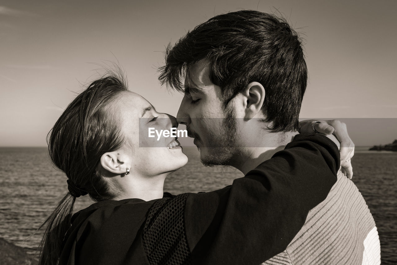 two people, romance, men, togetherness, adult, emotion, love, positive emotion, black and white, portrait, young adult, person, women, sky, ceremony, embracing, happiness, monochrome, nature, bonding, water, portrait photography, headshot, beach, affectionate, smiling, land, sea, monochrome photography, female, lifestyles, kissing, leisure activity, casual clothing, child, outdoors, hugging