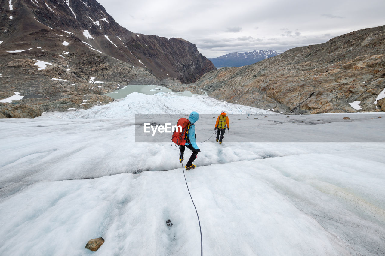 Rear view of people hiking on snow covered mountain