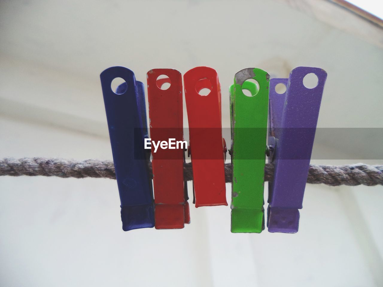 CLOSE-UP OF MULTI COLORED CLOTHESPINS ON WHITE