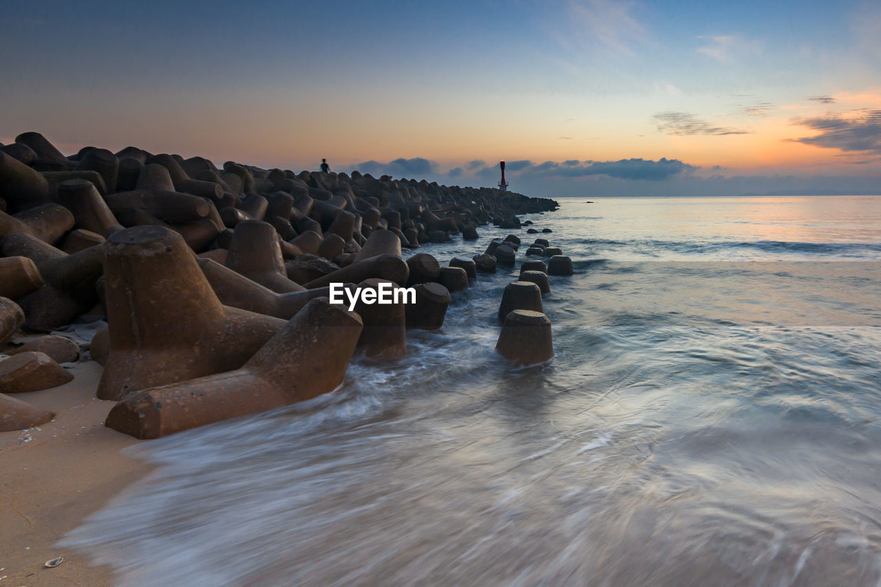 Rocks in sea against sky during sunrise