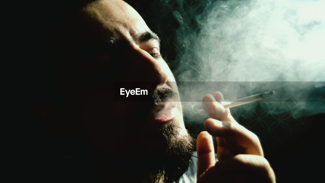 Close-up of man smoking in dark