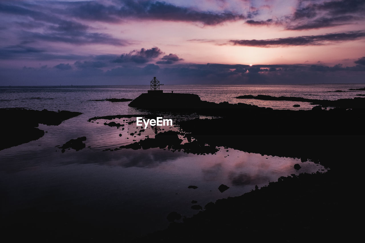 SCENIC VIEW OF ROCKS IN SEA AGAINST SKY DURING SUNSET