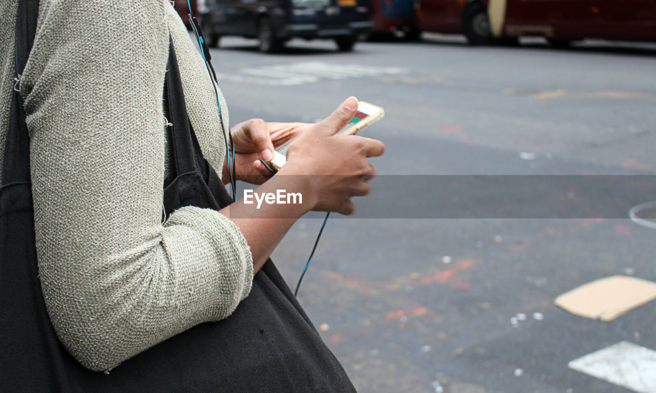 MIDSECTION OF MAN USING MOBILE PHONE