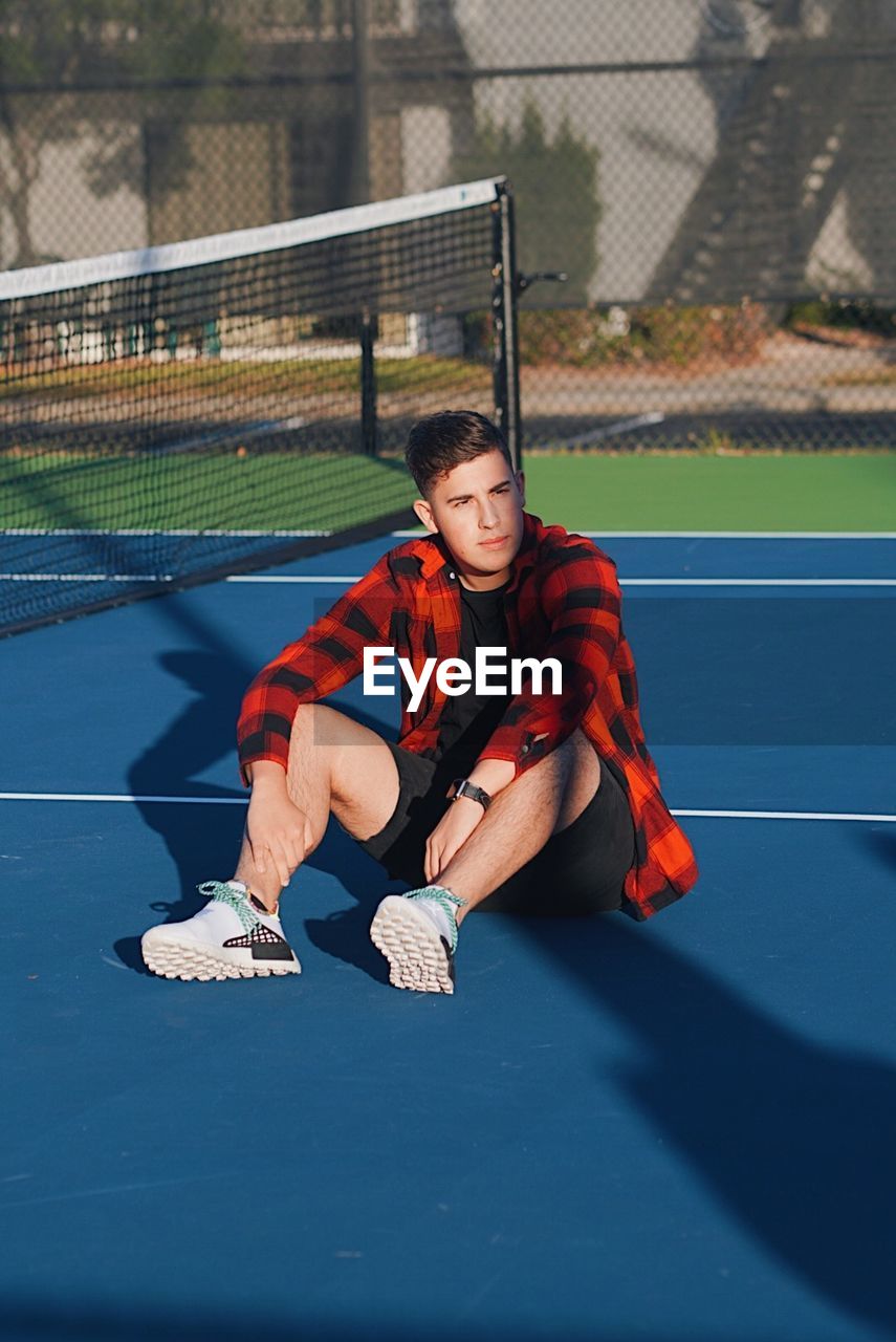 Man in flannel on bright colored tennis court