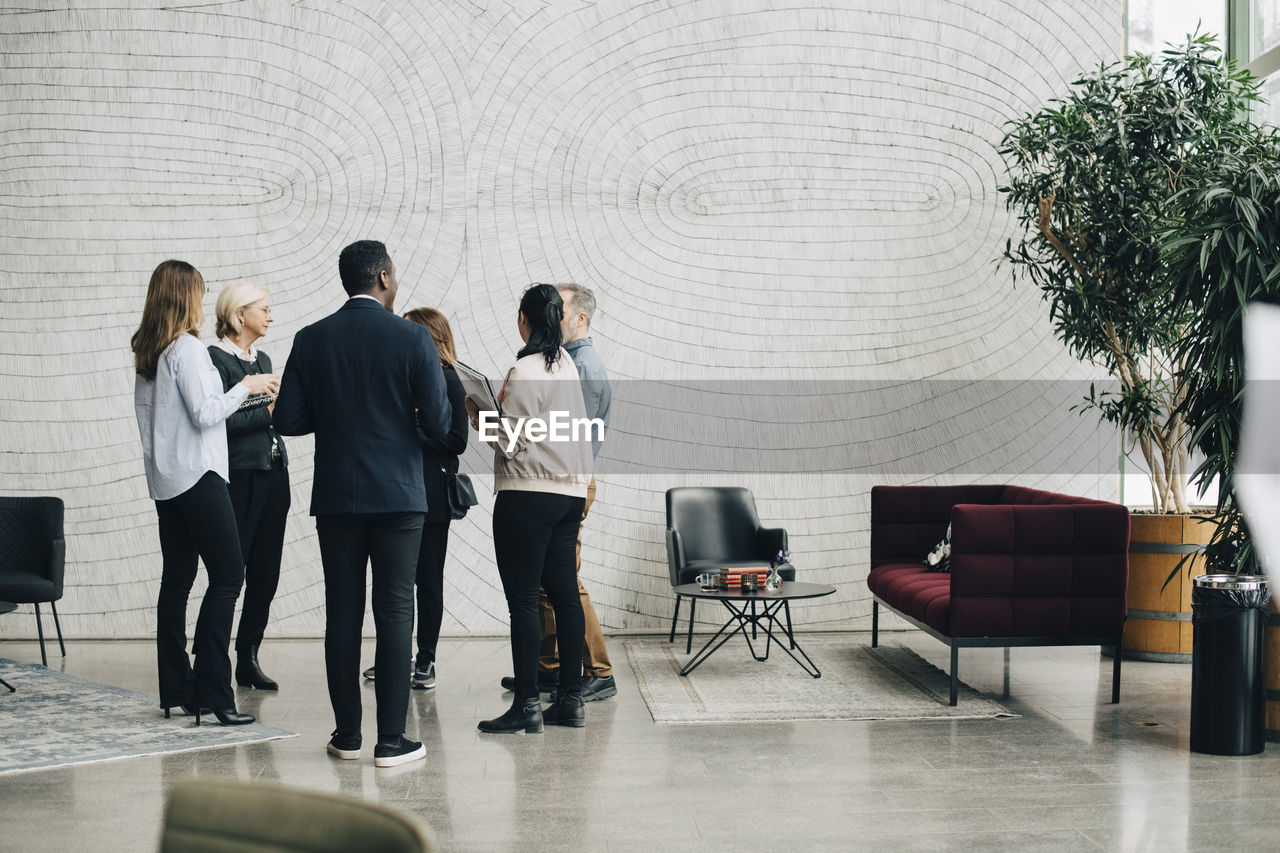 Business people discussing while standing in meeting at office