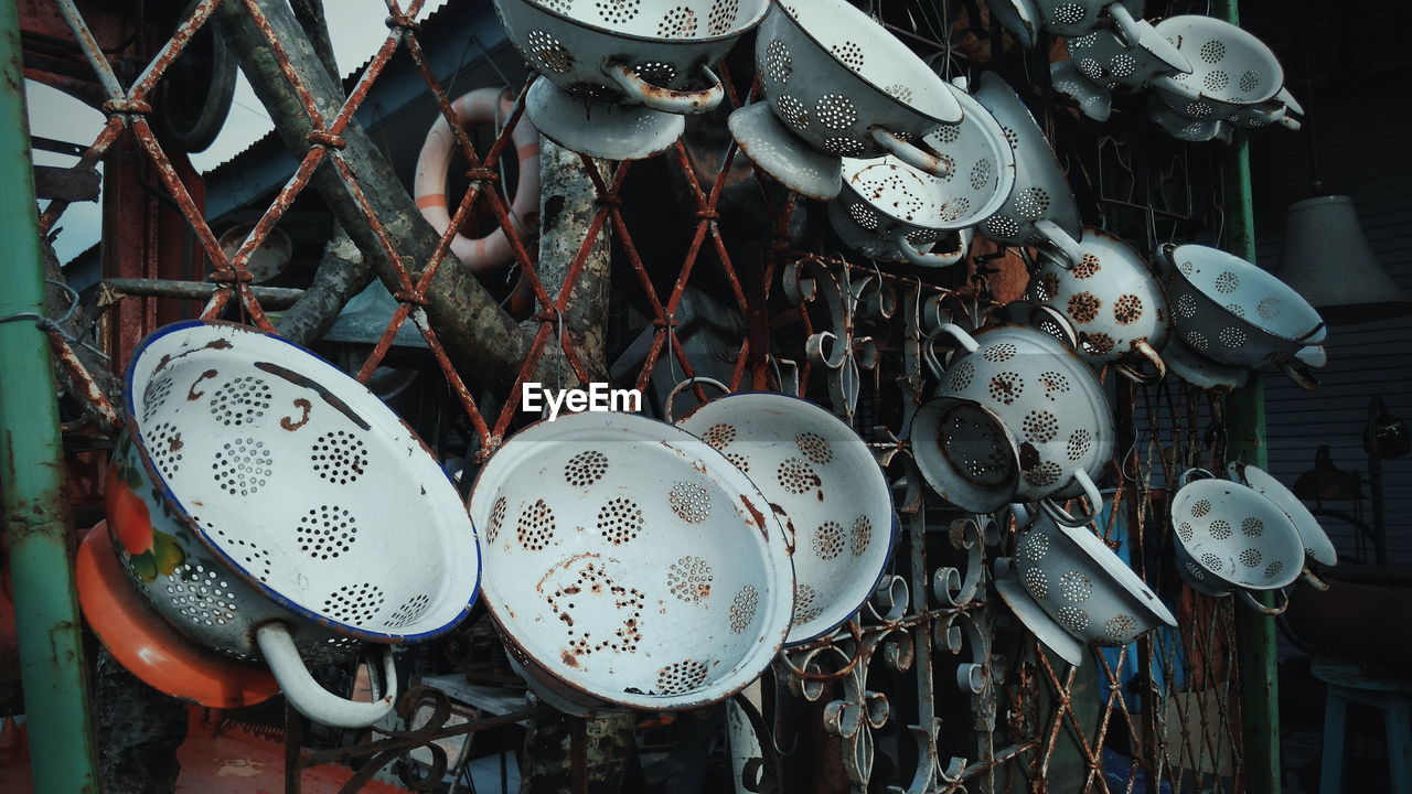 Close-up of abandoned containers hanging against fence