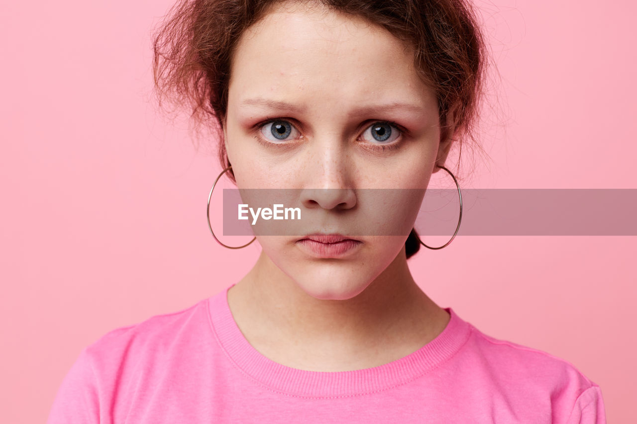 Portrait of teenager girl against pink background