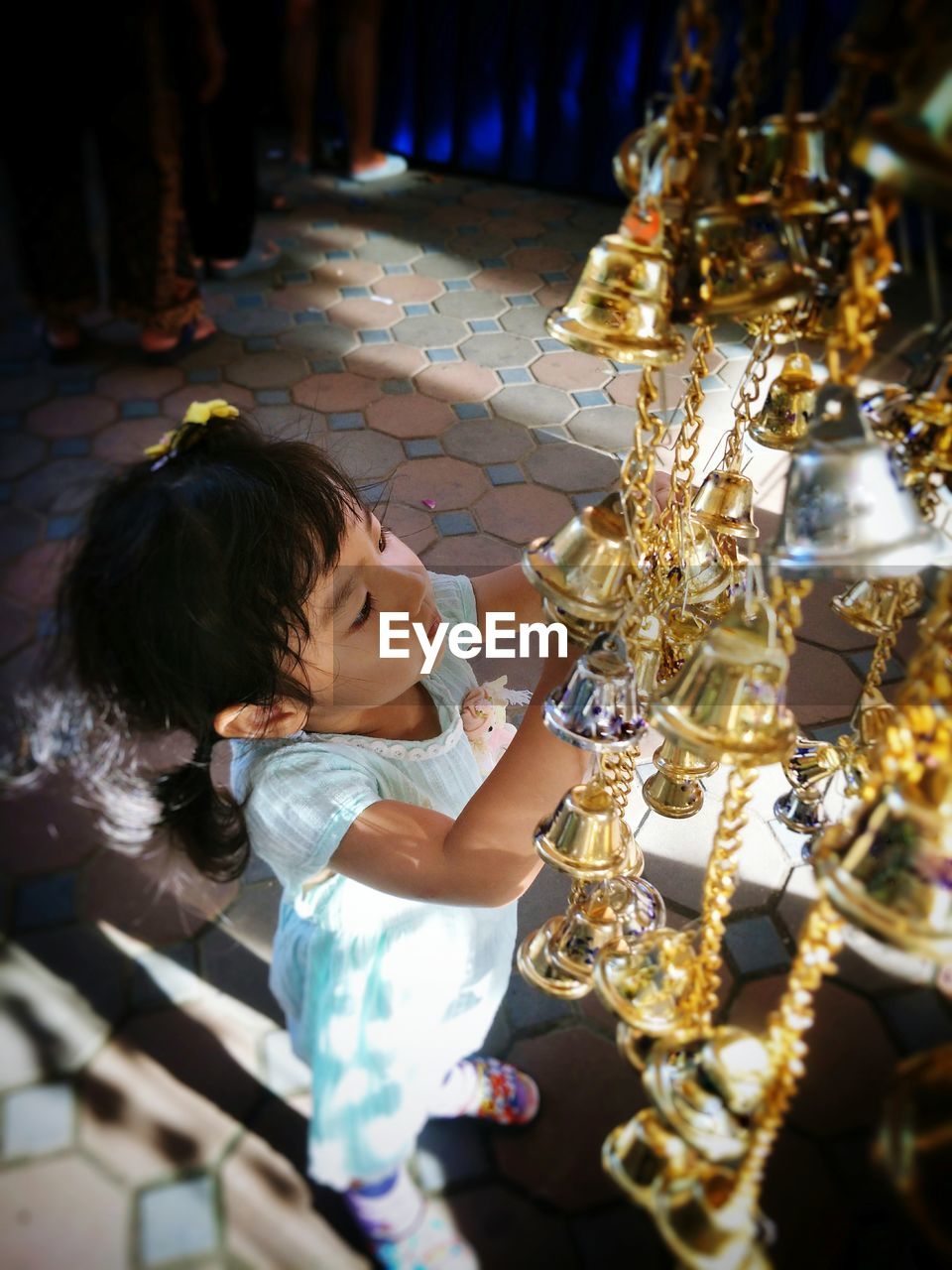 Full length of girl playing with bells hanging at shop