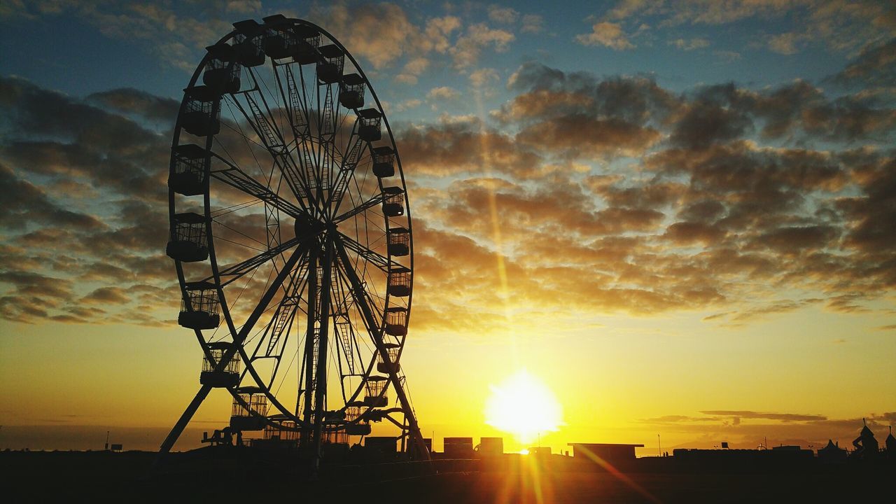 LOW ANGLE VIEW OF FERRIS WHEEL AGAINST ORANGE SKY