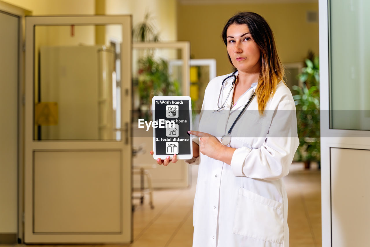 Portrait of female doctor showing digital tablet with messages