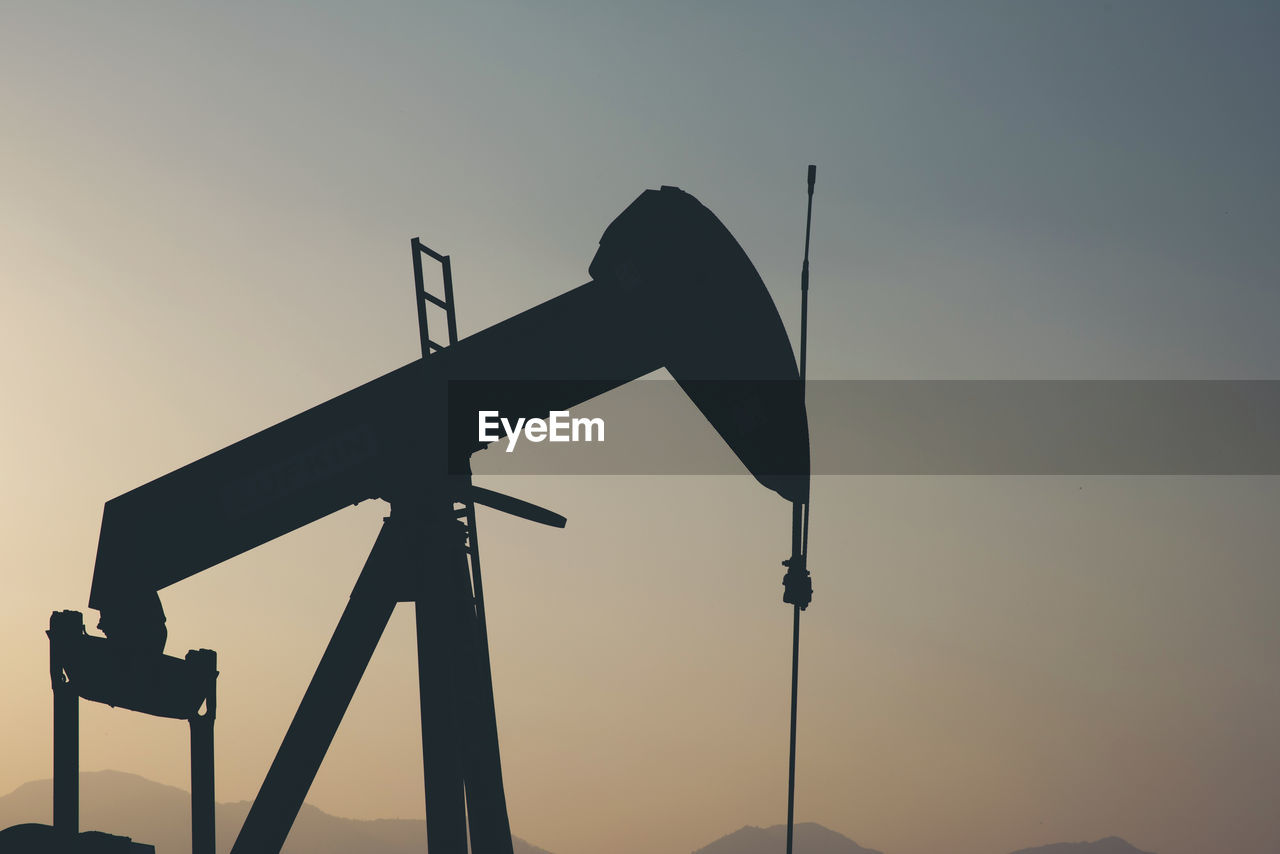 Low angle view of silhouette crane against sky during sunset