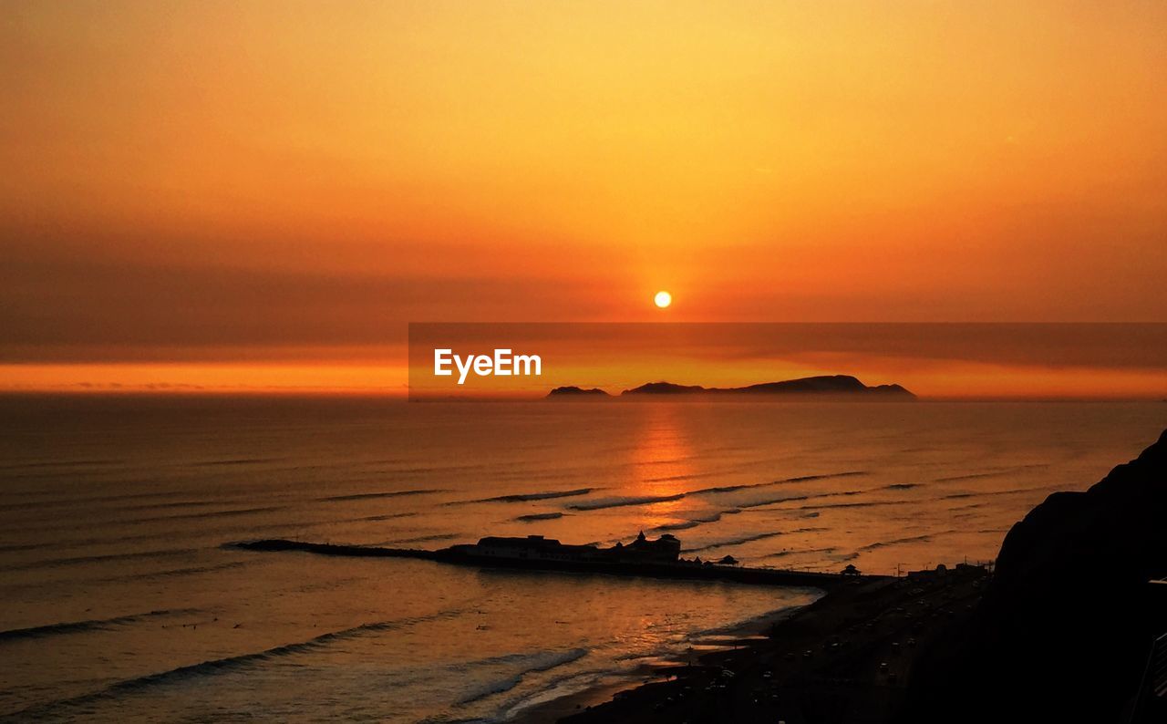 Scenic view of sea against orange sky