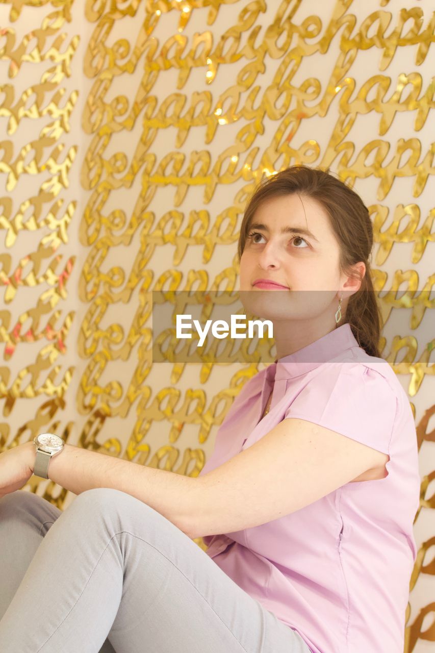Woman sitting against patterned wall