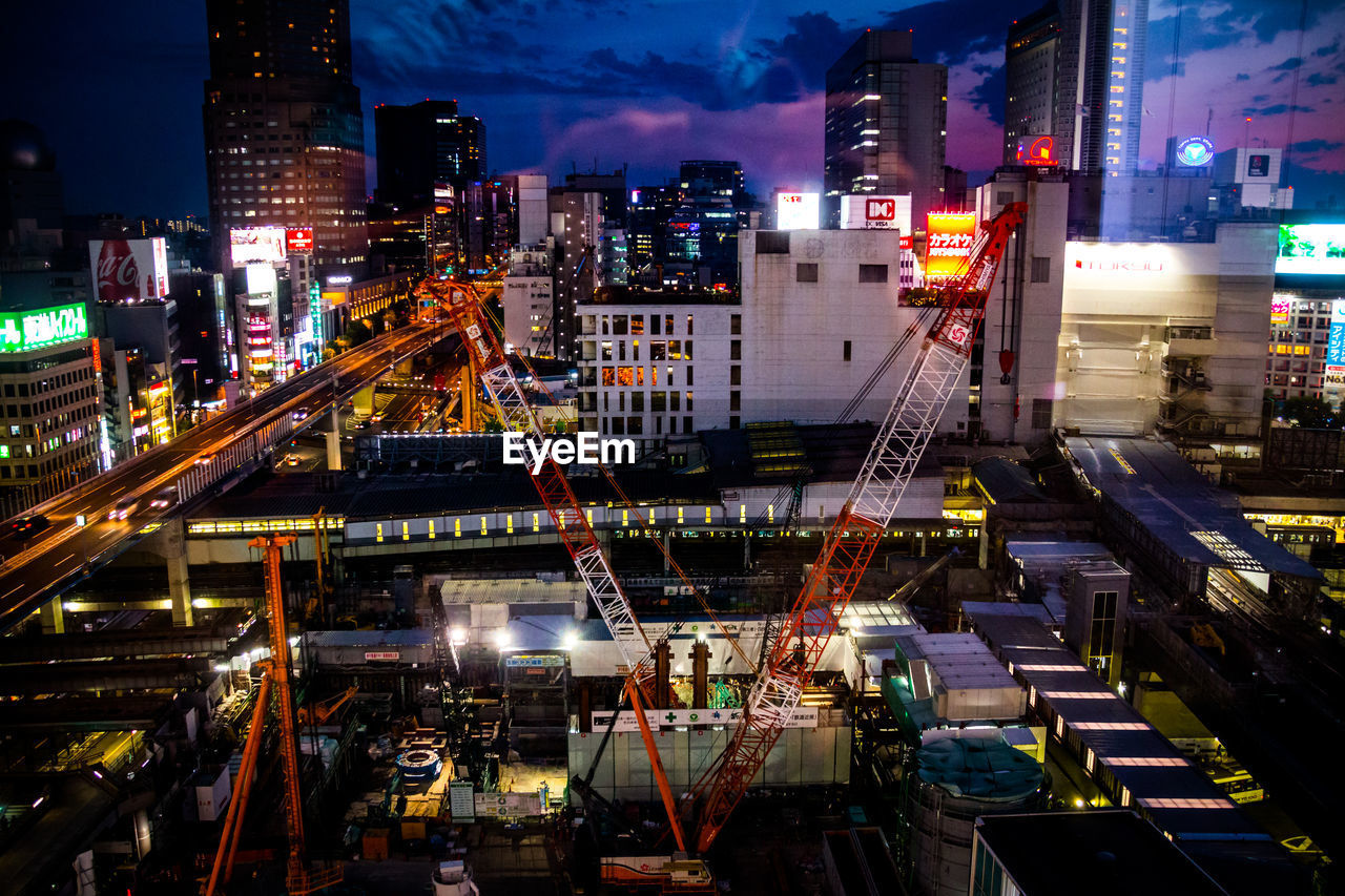 High angle view of cranes at construction site in city at night