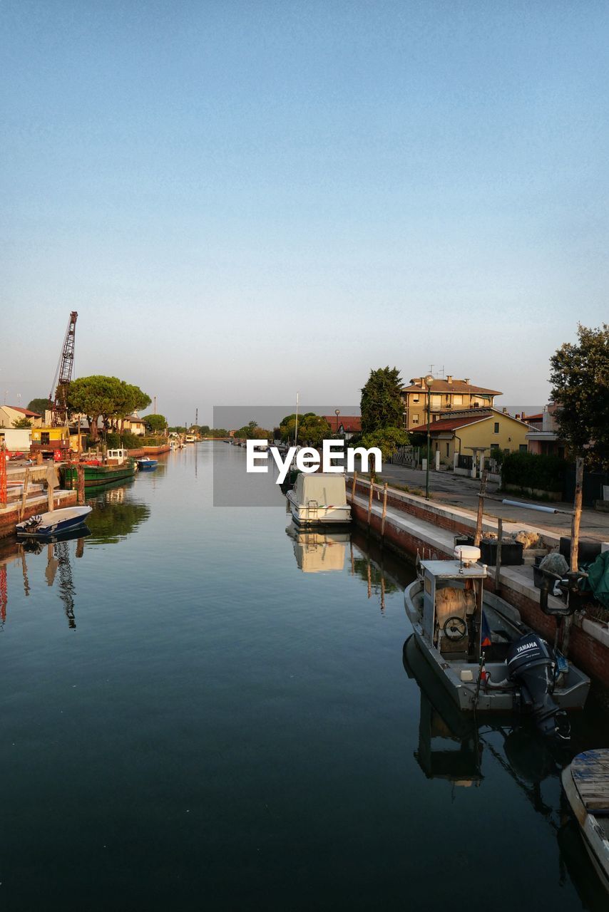 BOATS IN RIVER BY BUILDINGS AGAINST SKY