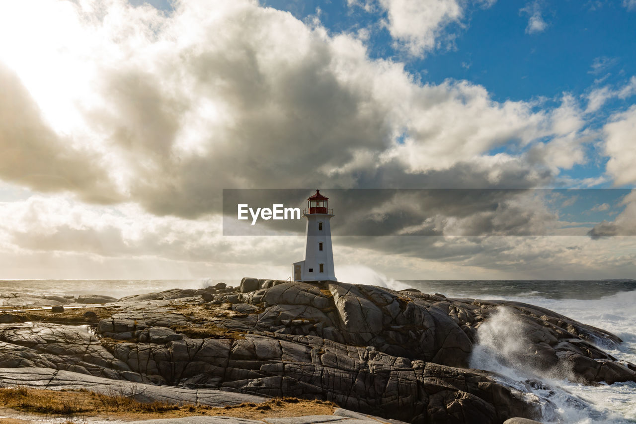 Lighthouse by sea against sky