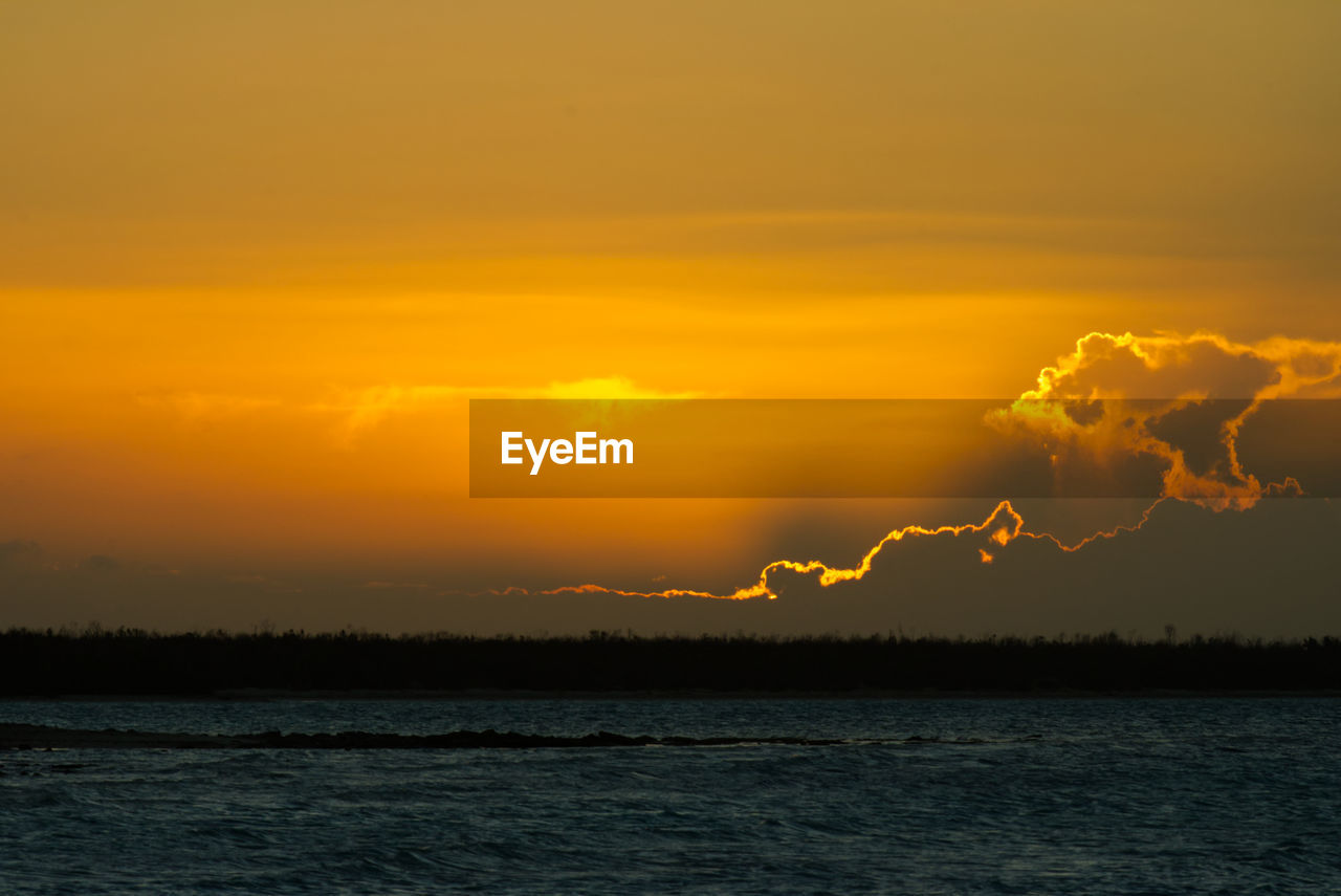 Scenic view of sea against orange sky at dusk