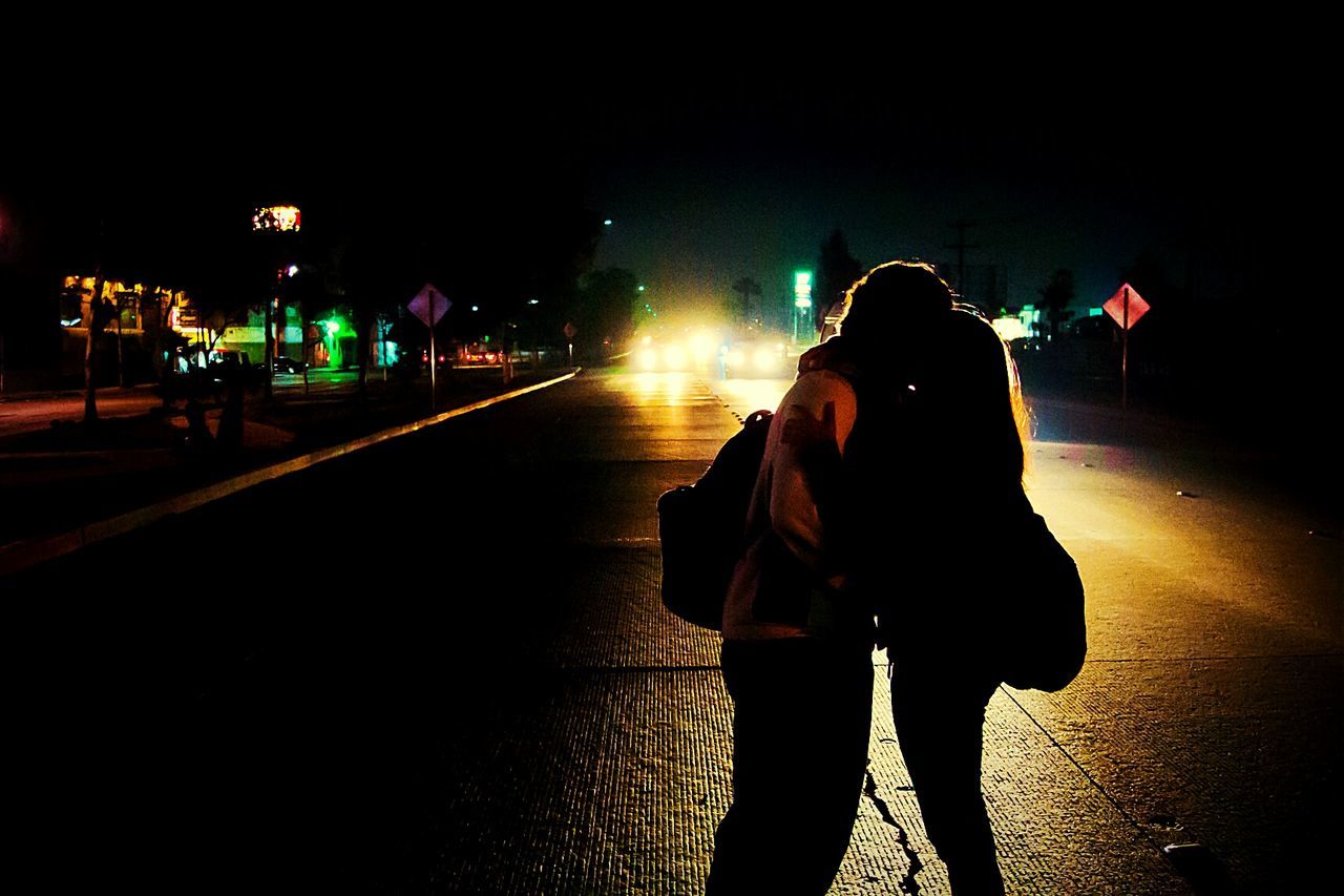 Silhouette couple kissing on street at night