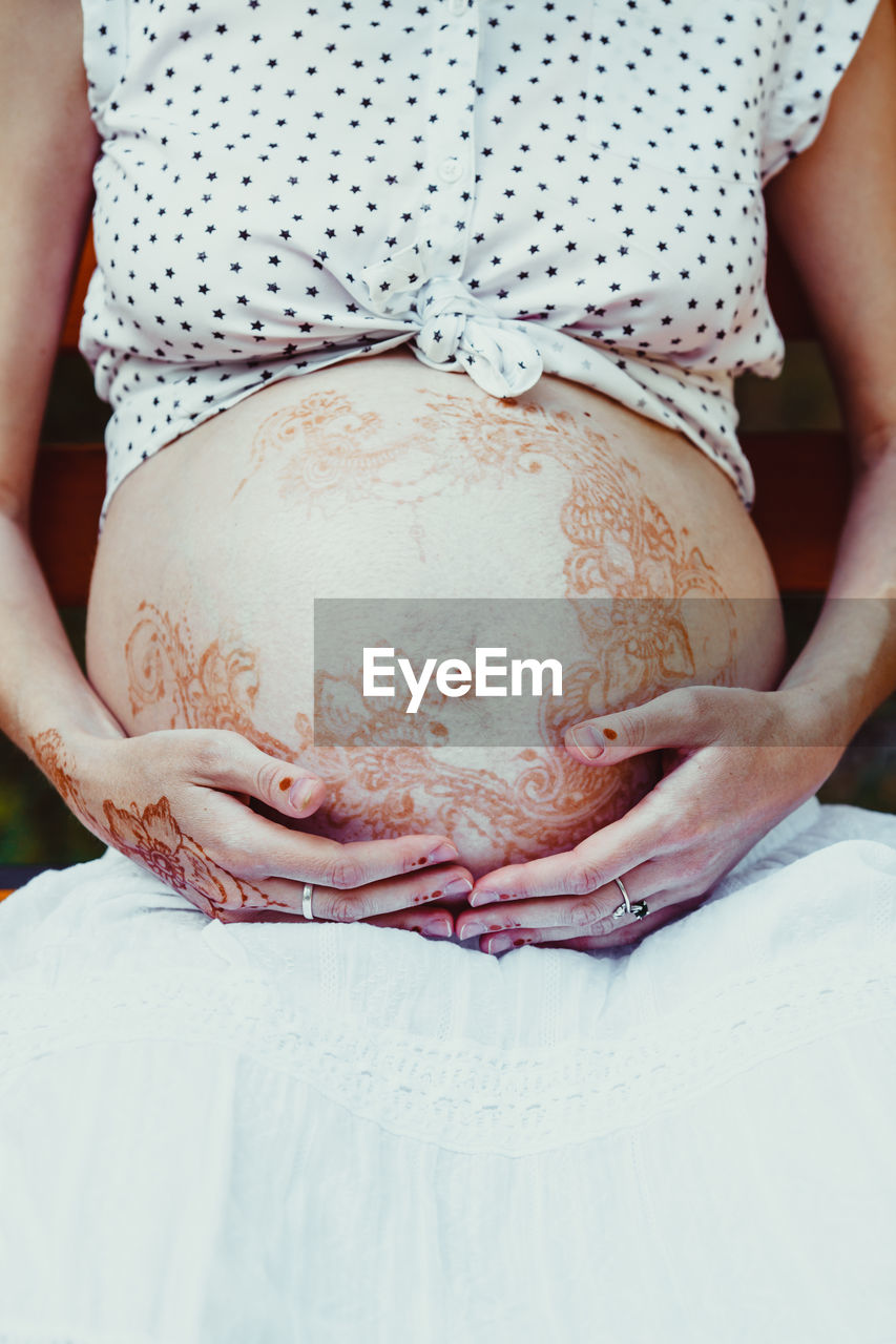 Midsection of pregnant woman with henna tattoo