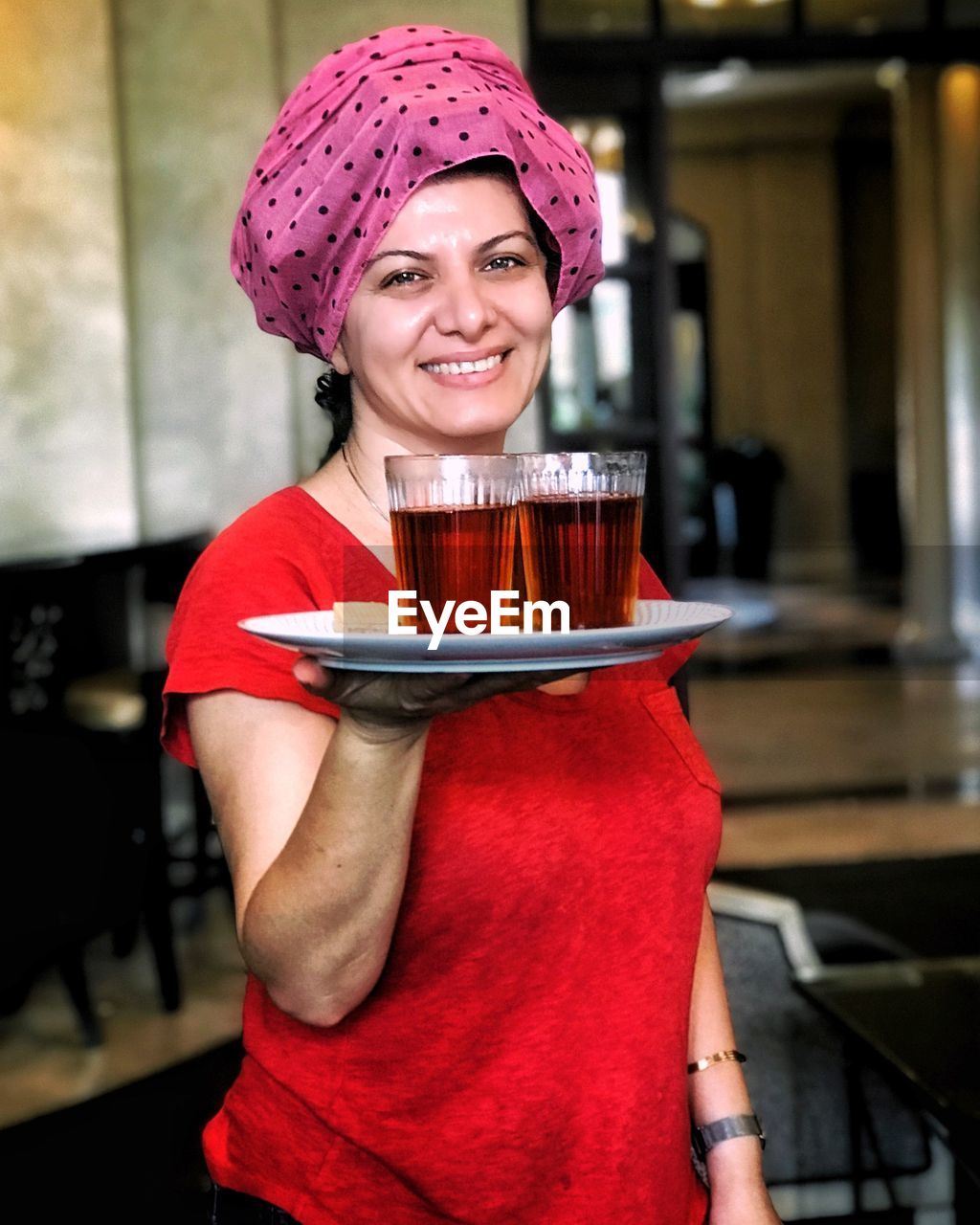 Portrait of smiling woman holding plate with drinks